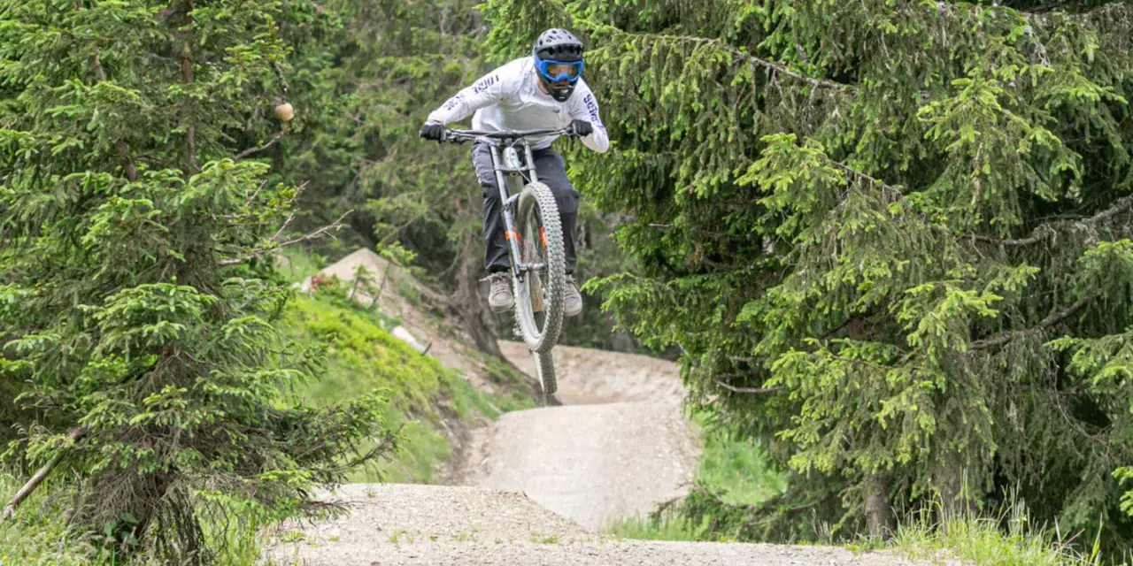Mountainbiker springt über eine Schanze im Wald. Die **Halde Hoppenbruch** bietet eine tolle Kulisse für diesen Sprung.