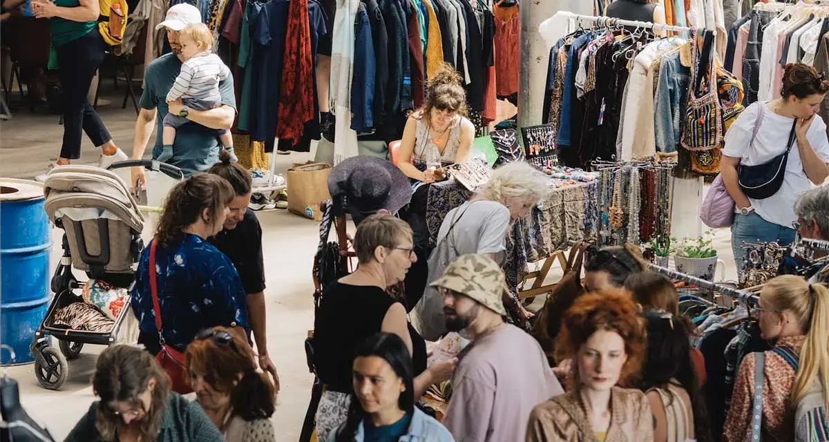 Menschen stöbern auf einem belebten **bazar de nuit** nach Kleidung und Accessoires.