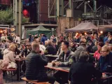 Menschen genießen Speisen und Getränke auf dem Street Food Festival Duisburg. Viele Besucher sitzen an langen Tischen und unter Zelten.