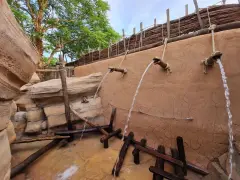 Wasserfälle speien auf einem Abenteuerpfad im Phantasialand. Holz und Felsen schaffen eine rustikale Atmosphäre.