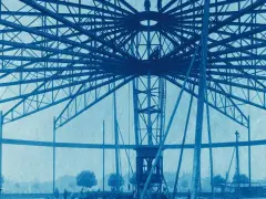 Bau des Riesenrades am GHH Oberhausen. Die Stahlkonstruktion ragt in den Himmel, Arbeiter sind auf der Spitze zu sehen.