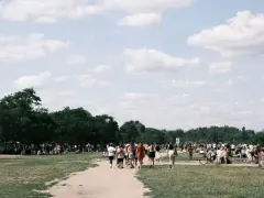 Menschen strömen über eine Wiese, unter Bäumen und Zelten. Ein sonniger Tag, wo ist Pfingsten was los?