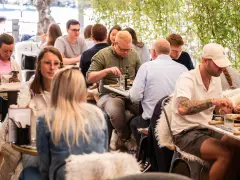 Leute genießen ein entspanntes St. Louis Frühstück im Freien, umgeben von Grün.
