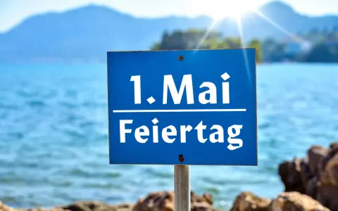 Schild am Strand: "1. Mai Feiertag". Die Sonne scheint über dem Meer, ideal für Veranstaltungen am 1. Mai.