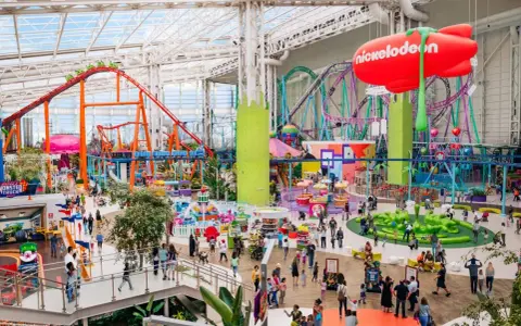 Buntes Treiben im Nickelodeon Park Deutschland mit Achterbahnen, Fahrgeschäften und vielen Besuchern.
