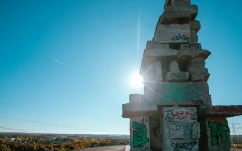Sonnenstrahlen brechen durch eine Betonkonstruktion auf der Halde Rheinelbe, die mit Graffiti übersät ist.