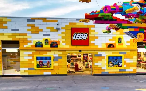 Bunte Lego-Steine schmücken das Gebäude und einen Baum. Ein lebendiger Lego-Freizeitpark lädt zum Spielen ein.