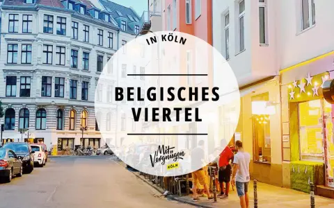 Abendstimmung im belgischen Viertel in Köln. Menschen sitzen vor einem beleuchteten Restaurant, Autos parken am Straßenrand.
