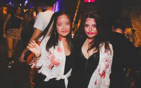 Zwei Frauen mit gruseligen Halloween-Schminkereien und blutigen Outfits feiern in der Halle Tor 2.