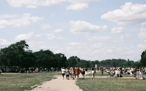 Menschen strömen über eine Wiese, unter Bäumen und Zelten. Ein sonniger Tag, wo ist Pfingsten was los?