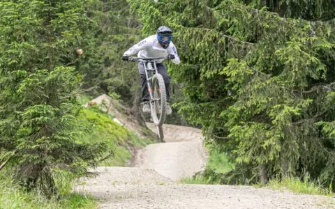Mountainbiker springt über eine Schanze im Wald. Die **Halde Hoppenbruch** bietet eine tolle Kulisse für diesen Sprung.