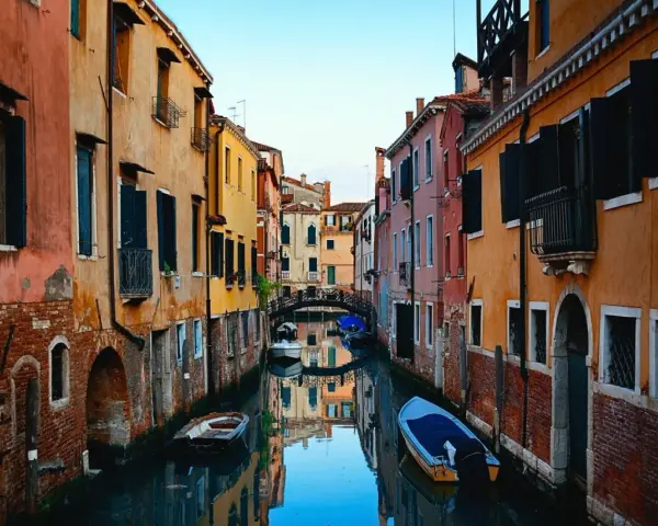 Bunte Häuser säumen einen Kanal in Venedig. Kleine Boote treiben auf dem Wasser. Ein kleiner Bogenbrücke überspannt den Kanal. Das ist, was man in Venedig gesehen haben muss.