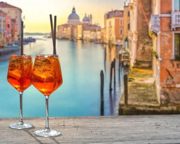 Zwei Aperol Spritz auf einem Holztisch mit Blick auf den Canal Grande in Venedig. Perfekt für einen Aperitif in der spritz bar.