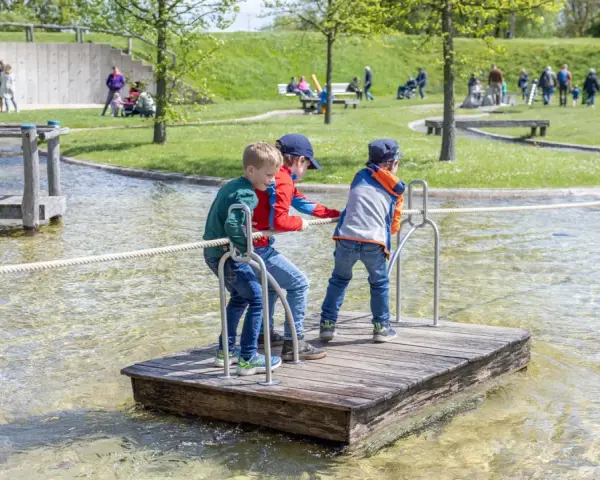 Drei Jungen auf einem Floß im Wasserspielplatz, der an ein Schiffshebewerk erinnert.