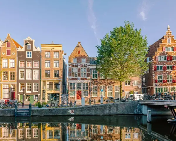 Bunte Grachtenhäuser spiegeln sich im Wasser. Fahrräder säumen den Kanal. So viel **was kann man in Amsterdam machen**!