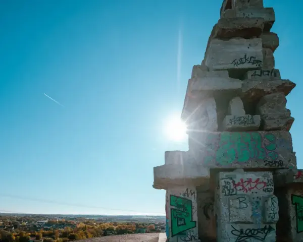 Sonnenstrahlen brechen durch eine Betonkonstruktion auf der Halde Rheinelbe, die mit Graffiti übersät ist.