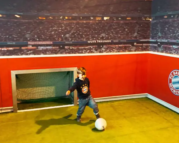 Kleiner Junge feiert seinen Allianz Arena Kindergeburtstag und kickt im FC Bayern Trikot.