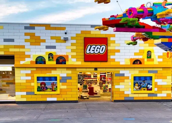 Bunte Lego-Steine schmücken das Gebäude und einen Baum. Ein lebendiger Lego-Freizeitpark lädt zum Spielen ein.