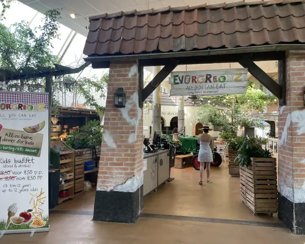 Im Center Parcs Restaurant "Evergreenz" lockt ein Buffet. Eine Frau im Sommerkleid geht vorbei.