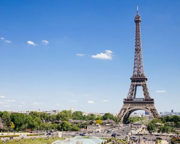 Eiffelturm in Paris, mit Menschen im Park. Hier gibt es viele Paris Tipps und Tricks für Ihren Besuch.