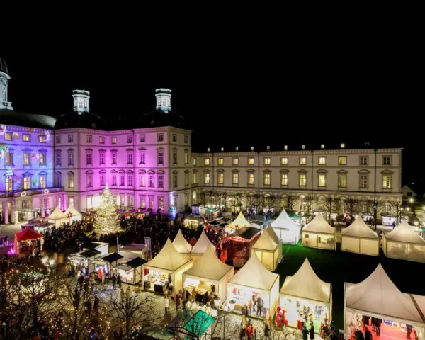 Einzigartiger Weihnachtsmarkt Bensberg vor beleuchtetem Schloss. Viele Stände und ein großer Weihnachtsbaum laden zum Bummeln ein.