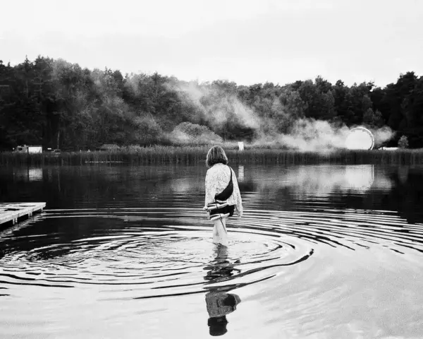 Ein Mädchen watet im Wasser, während im Hintergrund Nebel und eine Lichtinstallation zu sehen sind. Ein friedlicher Moment beim nachtigall festival.