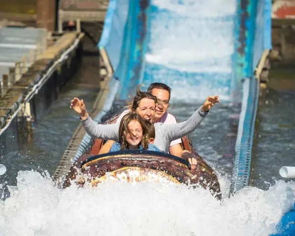 Familie hat Spaß auf einer spritzigen Wasserbahn im Freizeitpark.