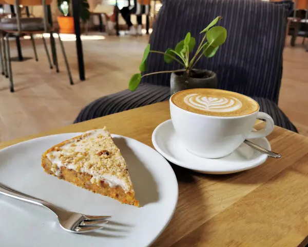 Ein Stück Kuchen mit Nüssen und eine Latte Art im **Kuchen Cafe**.