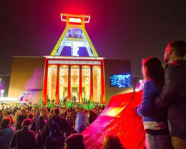 Ein Paar genießt die stimmungsvolle Nachtveranstaltung "Extraschicht Bochum" vor dem beleuchteten Deutschen Bergbau-Museum.