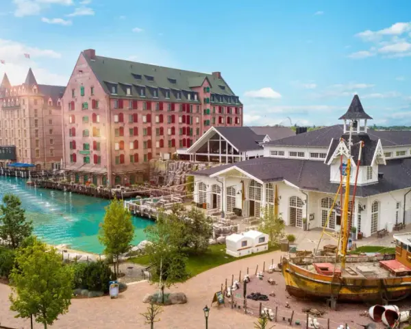 Ein malerischer Kanal fließt vorbei an bunten Gebäuden und einem alten Schiff. Das ist das charmante Themenhotel im Europa-Park.