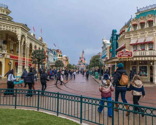 Menschen schlendern die Hauptstraße entlang, vorbei an Geschäften und dem Schloss. Ein Tag im Disneyland, vielleicht mit einem Disneyland Fastpass für die Attraktionen.