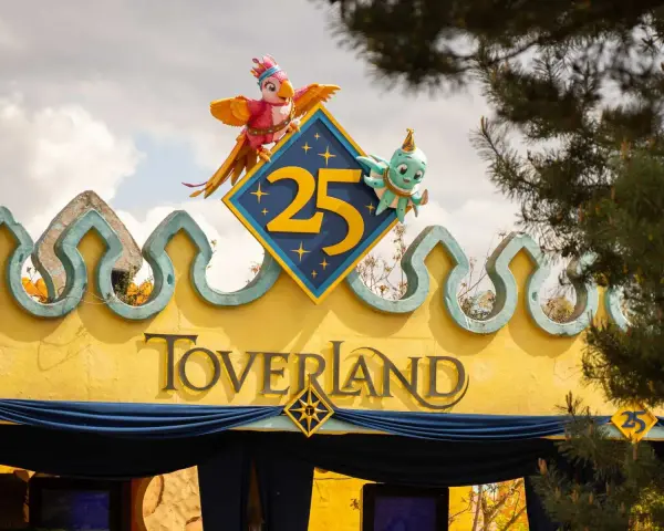 Bunte Figuren feiern 25 Jahre Toverland Freizeitpark. Ein Papagei und ein Oktopus zieren das Jubiläumslogo über dem Eingang.
