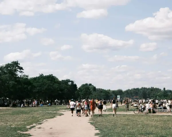 Menschen strömen über eine Wiese, unter Bäumen und Zelten. Ein sonniger Tag, wo ist Pfingsten was los?