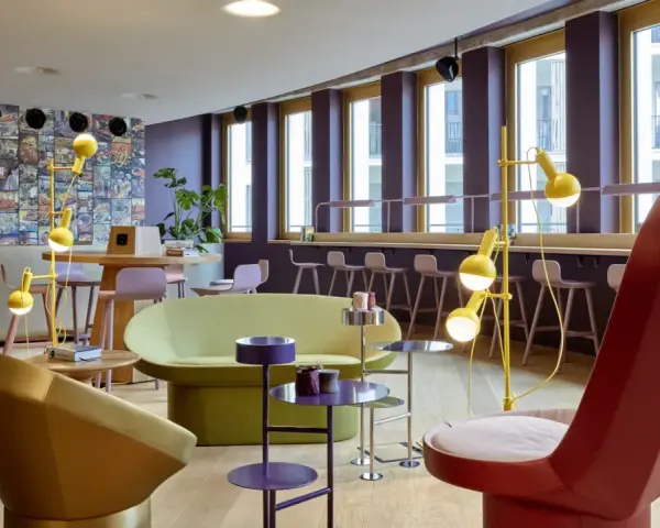 Ein bunter, moderner coworking space cologne mit auffälligen Möbeln, Comic-Wand und gelben Stehlampen.
