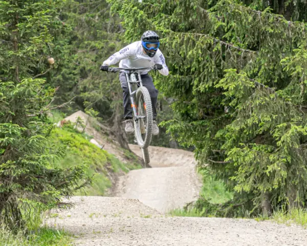 Mountainbiker springt über eine Schanze im Wald. Die **Halde Hoppenbruch** bietet eine tolle Kulisse für diesen Sprung.