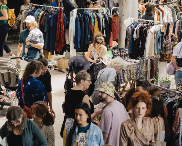 Menschen stöbern auf einem belebten **bazar de nuit** nach Kleidung und Accessoires.