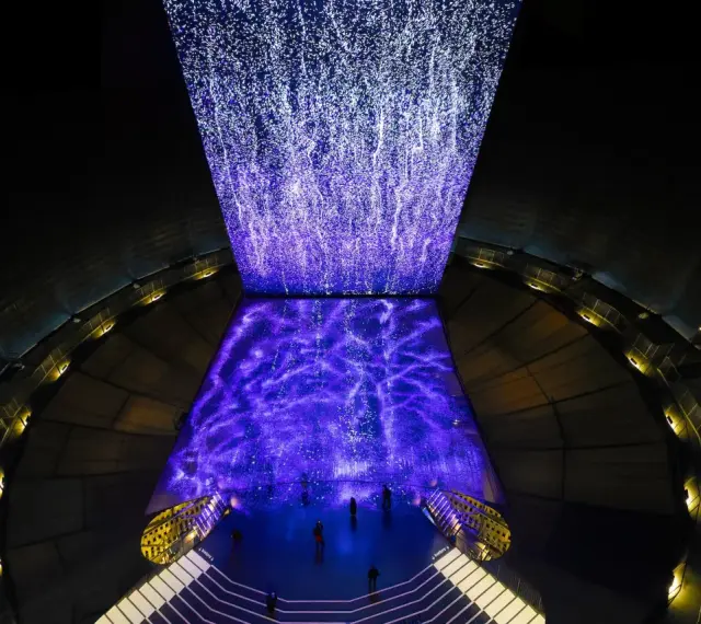 Im Gasometer Oberhausen erstrahlt eine Projektion aus tausenden Lichtpunkten, die wie ein Sternenhimmel oder ein Wasserfall wirken.