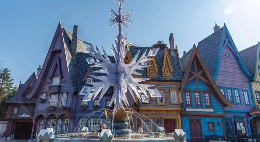 Ein eisiger Brunnen mit Schneeflocken-Dekor vor bunten Häusern, wie in einem **frozen Disneyland**.