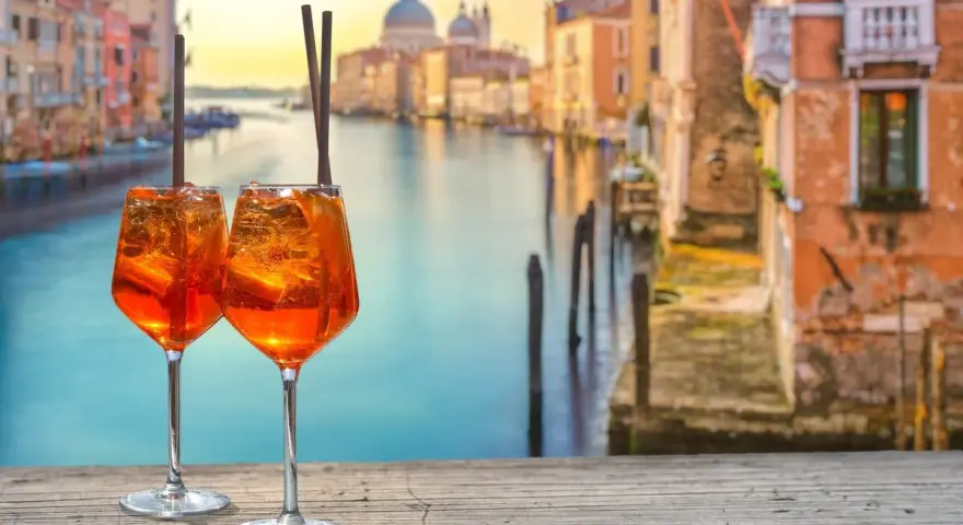 Zwei Aperol Spritz auf einem Holztisch mit Blick auf den Canal Grande in Venedig. Perfekt für einen Aperitif in der spritz bar.