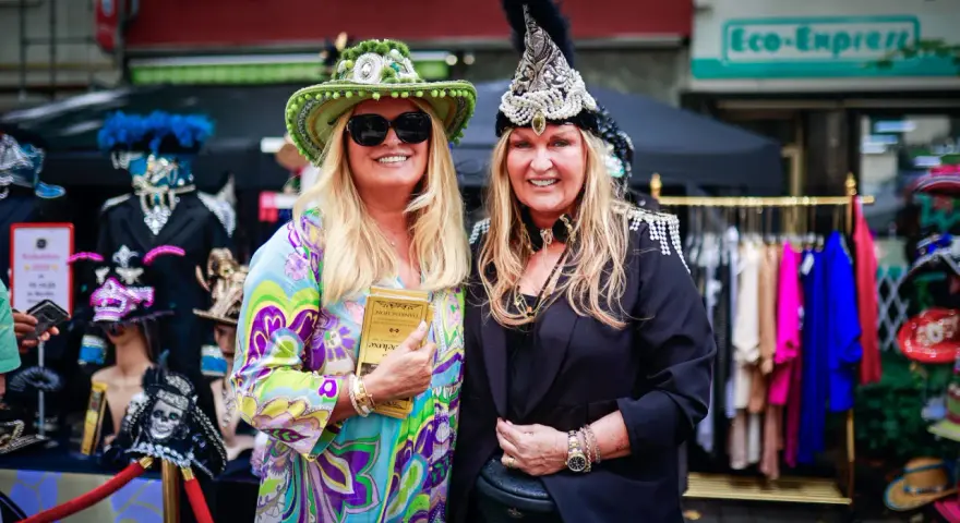 Zwei Frauen in bunten, auffälligen Outfits und Hüten genießen das Lindenthaler Sommerfest.