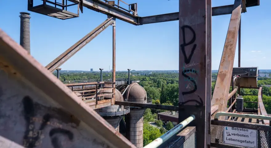 Industrielles Erbe in Duisburg: Rostige Stahlkonstruktionen und Kuppeln des Landschaftsparks Nord, mit Blick auf grüne Bäume und Gebäude.