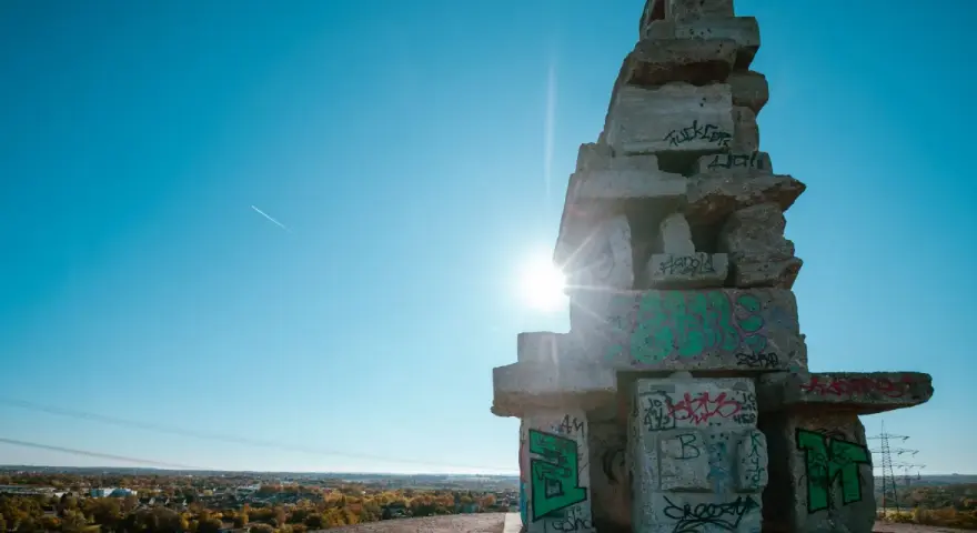 Sonnenstrahlen brechen durch eine Betonkonstruktion auf der Halde Rheinelbe, die mit Graffiti übersät ist.