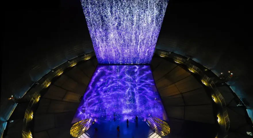 Im Gasometer Oberhausen erstrahlt eine Projektion aus tausenden Lichtpunkten, die wie ein Sternenhimmel oder ein Wasserfall wirken.