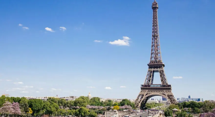 Eiffelturm in Paris, mit Menschen im Park. Hier gibt es viele Paris Tipps und Tricks für Ihren Besuch.