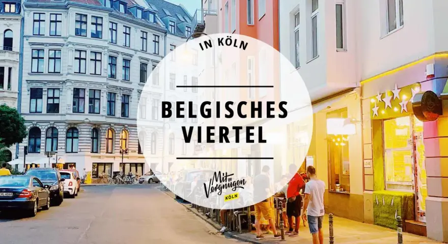 Abendstimmung im belgischen Viertel in Köln. Menschen sitzen vor einem beleuchteten Restaurant, Autos parken am Straßenrand.
