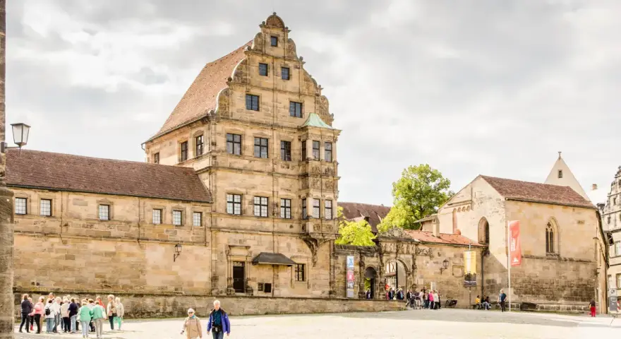 Historische Gebäude im Herzen der Bamberger Innenstadt, mit Menschen, die den Platz erkunden.