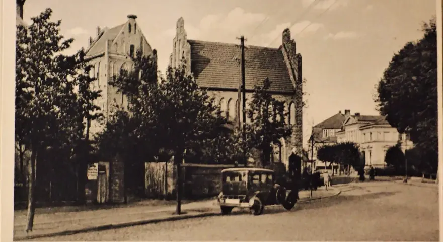 Alte Ansicht der Templiner Altstadt mit einem historischen Auto auf der Straße und markanten Gebäuden im Hintergrund.