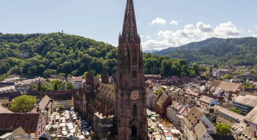 Blick auf den Freiburger Münsterplatz mit Marktständen. Hier kann man in Freiburg viel entdecken, von der beeindruckenden Architektur bis zum lebhaften Treiben.