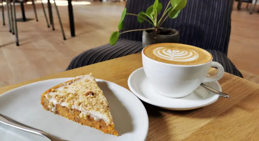 Ein Stück Kuchen mit Nüssen und eine Latte Art im **Kuchen Cafe**.