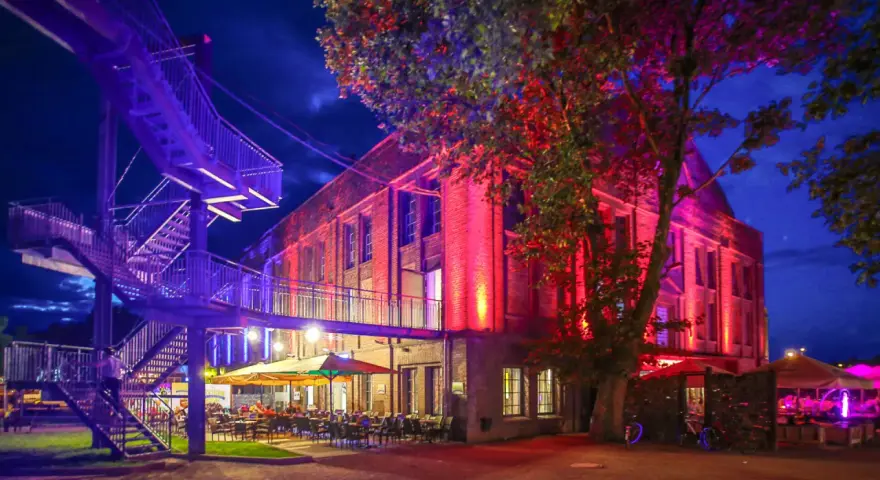 Abendstimmung mit bunten Lichtern und einer Treppe, die zum "Extraschicht Dorsten" führt.